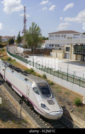 Ronda, malaga, spanien moderner Hochgeschwindigkeitszug, der an einem sonnigen Tag durch ein Vorstadtgebiet fährt, vorbei an Gebäuden und einem Kommunikationsturm, ronda, Stockfoto