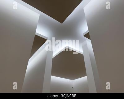 Futuristisches Deckendesign mit sich kreuzenden geometrischen Paneelen und sanfter, diffuser Beleuchtung. Minimalistisches architektonisches Detail, das einen abstrakten Stern bildet Stockfoto
