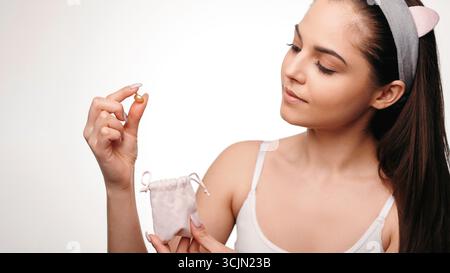 Glückliche, lächelnde junge Frau, die eine Ölpille hält Stockfoto
