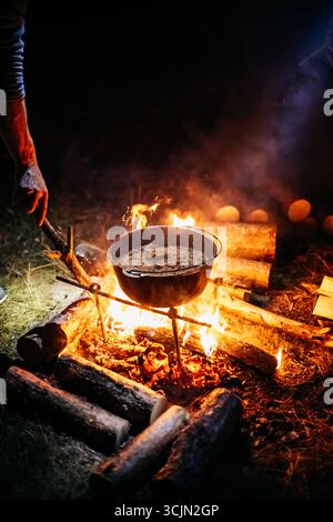 Junger Mann, der draußen Essen kocht Stockfoto