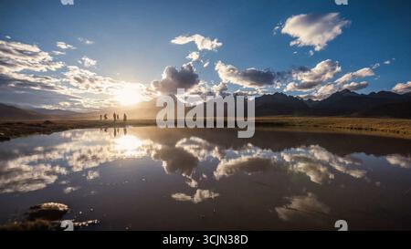 Die Menschen spiegelten sich in einem ruhigen Bergsee Stockfoto