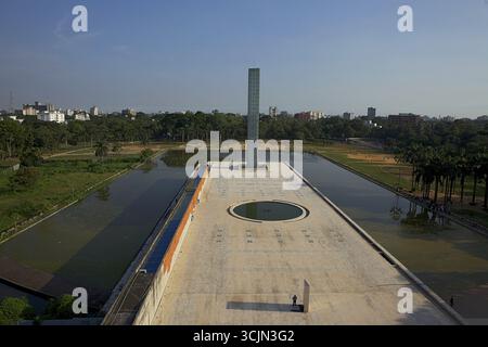 Aus der Vogelperspektive das Independence Monument, ein hoch aufragendes Gebäude, das sich in ruhigen Gewässern inmitten von üppigem Grün spiegelt und einen markanten Kontrast zum klaren Himmel bildet, Hazarali, Khulna Division, Bangladesch. Stockfoto