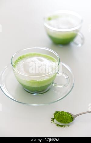 Eine hausgemachte zeremonielle Matcha-Latte in einer Glasschale, garniert mit cremigem Schaum, zubereitet mit hochwertigem japanischem Grünteepulver. Stockfoto