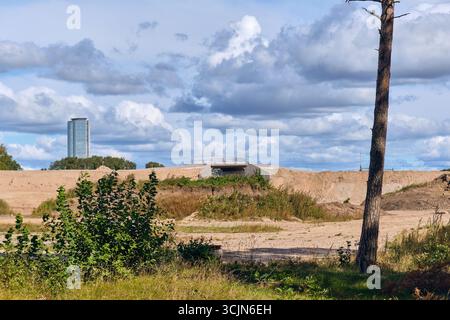 Halmstad, Schweden; 25. August 2023: Sanddamm mit Fußgängerunterführung und hohem Büroturm, der während eines neuen Infrastrukturprojekts in über dem Gebäude ragt Stockfoto