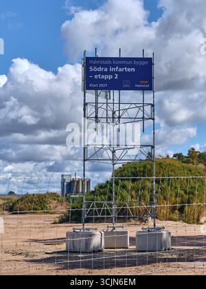 Halmstad, Schweden; 25. August 2023: Bauschild für Södra Infarten, zweites Projekt hinter Bauzaun mit Industriesilos im Hintergrund, Comp Stockfoto