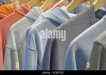 Persönliche Garderobe oder Schaufenster, Gruppe von Hoodies und Sweatshirts in verschiedenen Farben auf Kleiderbügeln, Nahaufnahme, abstrakte Textilindustrie Hintergrund Stockfoto