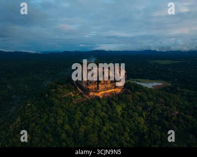 Die legendäre Lion Rock Festung erhebt sich majestätisch inmitten eines smaragdgrünen Waldes unter einem dramatischen Himmel, Lion Rock, Zentralprovinz, Sri Lanka. Stockfoto