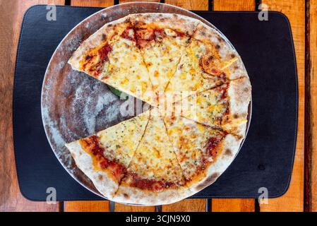 Pizza Margherita auf runder Platte in Stücke geschnitten, italienisches Gebäck im Pizzeria-Restaurant Stockfoto