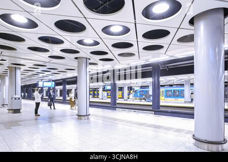 Amsterdam Schiphol Airport, Holland, 25. August 2025. Leute, die im Zug auf dem Bahnsteig warten. Weitwinkelansicht, hell beleuchtet Stockfoto