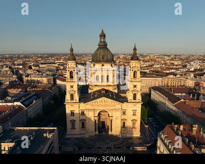 Blick aus der Vogelperspektive auf die prächtige Stephansbasilika, die sich im warmen Glanz der Sonne sonnt, ihre Kuppel und Türme, die die Skyline durchdringen, Budapest, Ungarn. Stockfoto