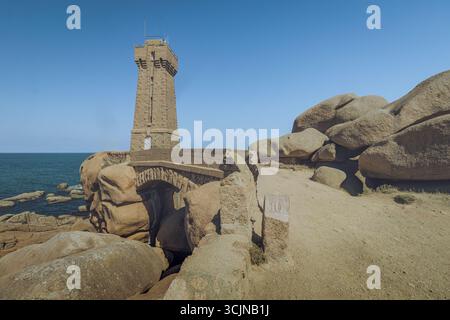 Blick auf die Männer der Leuchtturm Ruz steht hoch an der zerklüfteten, rosa Granitküste vor dem klaren blauen Himmel und dem Meer in Perros-Guirec, Bretagne, Frankreich. Stockfoto
