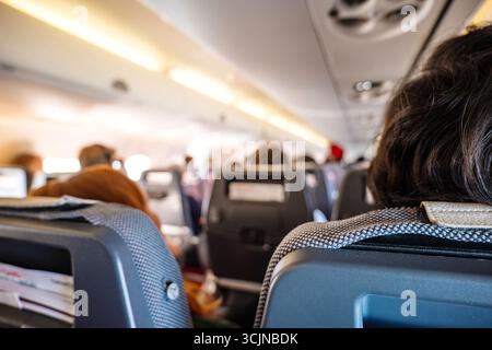Verschwommene Menschen in der Kabine eines kommerziellen Flugzeugs vor dem Start. Weitwinkel, Nahaufnahme, geringe Schärfentiefe, nicht erkennbare Personen Stockfoto