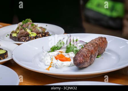 Traditionelles hausgemachtes Lammkafta oder Kofta-Kebab mit Sauce und Joghurt. Traditionelle arabische und türkische Küche. Halal-Essen. Stockfoto