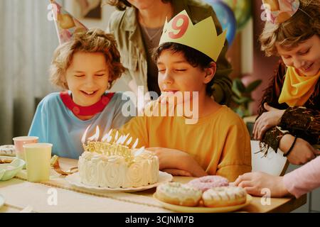 Multiethnische Kinder feiern Geburtstagsfeier mit Kuchen und Kerzen im Haus Stockfoto