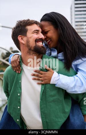 Glückliches multirassisches Paar, das draußen lächelt. Stockfoto