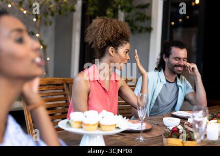 Verschiedene Freunde genießen eine Dinner-Party im Freien mit Cupcakes und lebhaften Gesprächen Stockfoto