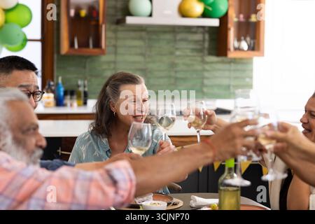 Mit Weingläsern toasten, Seniorenfreunde feiern zu Hause eine fröhliche Party Stockfoto