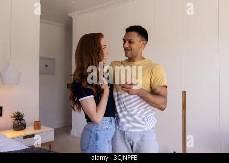 Junge Paare, die zu Hause im gemütlichen Wohnzimmer lachen und miteinander reden Stockfoto