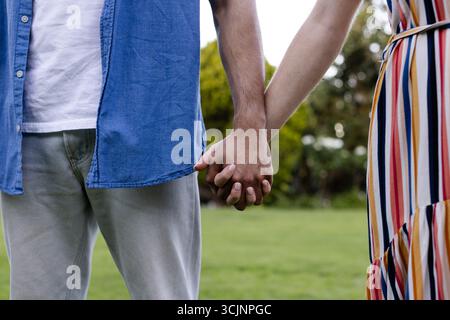 Ein junges Paar hält draußen Hände und genießt friedliche Momente im Park Stockfoto
