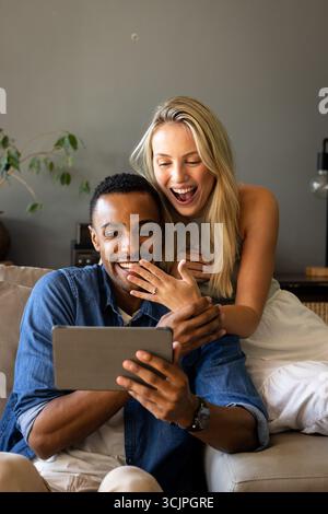 Paare sitzen auf der Couch und schauen sich ein Tablet an, um gemeinsam spannende Momente zu teilen Stockfoto