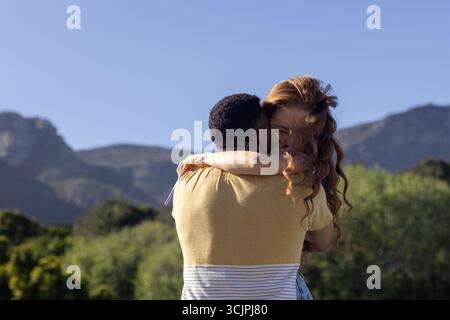 Ein junges Paar, das sich im Freien mit Bergen im Hintergrund umgibt und freudige Momente teilt Stockfoto