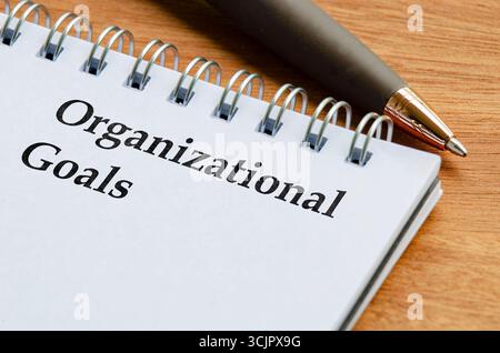 Schließen Sie den Notizblock mit den Worten Organisationsziele auf liniertem Papier, das flach auf einem Schreibtisch liegt Stockfoto