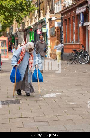 Ältere muslimische Frau mit Gehstöcken in East End London. Stockfoto