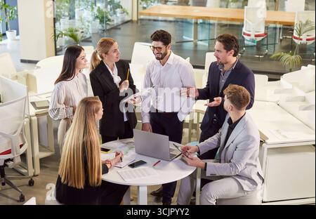 Junge Leute Gruppe von Unternehmensmitarbeitern, die während einer Konferenz bei einem Geschäftstreffen sprechen. Stockfoto