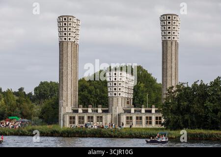 Segel-in-Parade des Sail Amsterdam, 20. August 2025, passiert ein kleines Boot die Lüftungstürme des Velser-Tunnels, Niederlande. Die Segel Amsterda Stockfoto