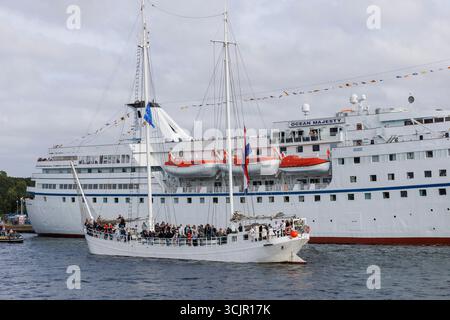 Segel-in-Parade der Sail Amsterdam, 20. August 2025, passiert ein zwei-Meister das ehemalige Kreuzfahrtschiff Ocean Majesty, das heute als Flüchtlingsunterkunft genutzt wird, ne Stockfoto