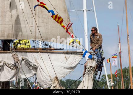 Segel-in-Parade der Sail Amsterdam, 20. August 2025, Seemann sitzt auf dem Bugspriet der zweimastigen Brig Le Phoenix, erbaut 1929 in den Niederlanden. Stockfoto
