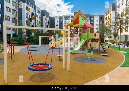 Farbenfroher Kinderspielplatz mit Gummibeschichtung, Schaukeln, Rutschen und anderer Ausrüstung in einem Wohngebiet Stockfoto