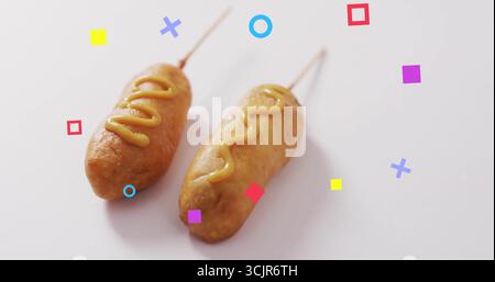Mit zwei zerschlagenen Maishunden auf weißem Tisch, Senfträufeln und geometrischen Formen Stockfoto