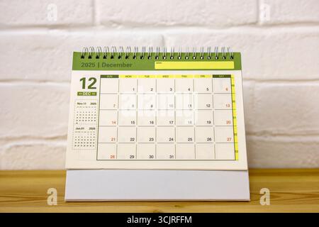 Kalender für Dezember 2025. Ein Desktop-Kalender und eine Uhr für die Planung auf dem Tisch Stockfoto