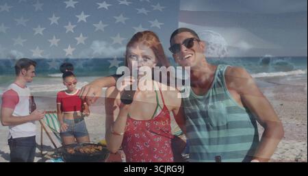Ein paar Bier in rotem Sommerkleid und gestreiftem Tanktop, das am Sandstrand plaudert, mit Grill Stockfoto
