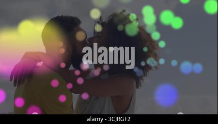 Küssende Schwarze Frau und bikultureller Mann, umarmt an ruhiger Küste unter klarem Himmel, buntes Bokeh Stockfoto