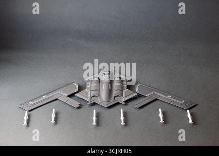 Close-up-Konzeptfoto eines B2 Spirit Tarnbomber-Spielzeugmodells mit abgetrennten Flügeln und Miniatur-Raketen, angeordnet auf Gradienten-Grafit-bac Stockfoto