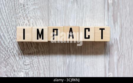 Impact ist ein Name aus Holzbuchstaben. Schreibtisch Stockfoto