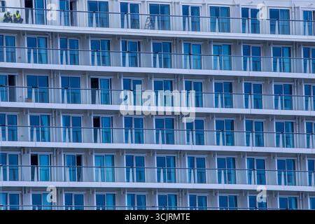 Wismar, Deutschland. August 2025. Zwei Arbeiter sitzen auf einem Kabinenbalkon auf dem neuen Kreuzfahrtschiff „Disney Adventure“ am ausgerüsteten Kai der Werft in Wismar. Nach rund sieben Jahren Bauzeit wird eines der größten Kreuzfahrtschiffe der Welt in den nächsten Tagen die Hansestadt verlassen. Die US-Reederei Disney Cruise Line übernahm das Schiff vom Insolvenzgut und lässt es von der Meyer Werft in Papenburg, Niedersachsen, bauen. Das Schiff wird ab Ende 2025 für die Disney Group in Südostasien im Einsatz sein. Quelle: Jens Büttne/dpa/Alamy Live News Stockfoto