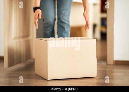 Unerkennbare Frau, die Pappkarton vom Boden nimmt Stockfoto