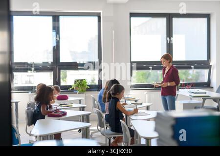 Zielgerichtete Schüler schreiben Notizen im Klassenzimmer, hören Lehrer zu. Stockfoto