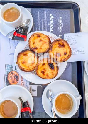 Lissabon, Portugal: Auf einem Tisch mit Tassen Kaffee steht ein Tablett mit Gebäck. Das Gebäck ist in einer ordentlichen Reihe angeordnet und die Tassen sind mit Kaffee gefüllt. Stockfoto
