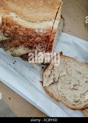 Ein Laib frisch gebackenes Brot liegt auf einem Papiertuch auf dem Tisch Stockfoto