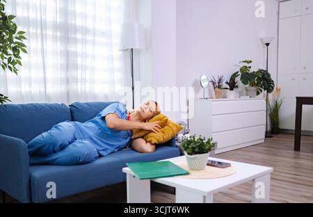 Erschöpfter Arzt, der nach langer Schicht im Krankenhaus auf dem Sofa ruht Stockfoto