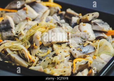 Nahaufnahme eines geschmackvollen Gerichts mit gekochten Heringsstücken, gemischt mit sautierten Zwiebeln, Karotten und Gewürzen Stockfoto