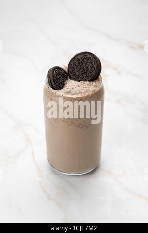 Cremiger Oreo-Milchshake in einem Glas, gekrönt mit Keksen auf Marmorhintergrund Stockfoto