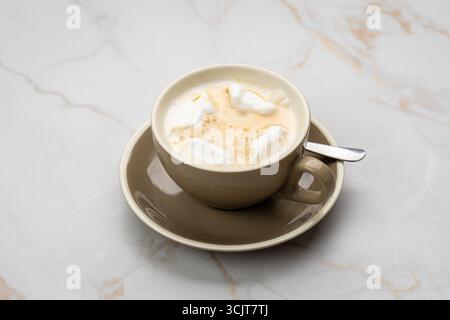 Cremiger Kaffee mit Marshmallows in einer beigen Tasse auf Marmorhintergrund, Blick von oben Stockfoto