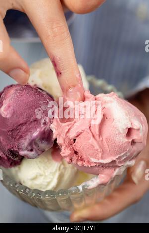 Fingerberührende cremige Eiskugeln in Glasschüssel in Nahaufnahme, Pastelltöne Stockfoto