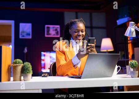 Glückliche Frau zu Hause, die sich am Telefon über Social Media-Feeds mit Live-Übertragungen von Online-Content-Erstellern anschaut. Fröhliche Person, die Social-Network-Anwendungen mit Livestreams von Influencern nutzt Stockfoto