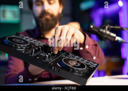 Nahaufnahme des Tutorials zum Filmen von DJ-Mischern durch Künstler, das dem Publikum Beispiele für Sampling auf dem Soundcontroller zeigt. Schwerpunkt auf moderner Musikausrüstung, präsentiert von einem Internetstar in unscharfem Hintergrund Stockfoto